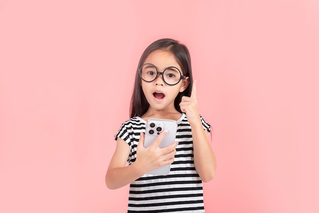 Kleines Mädchen spielt Handy, isoliert auf rosa Hintergrund