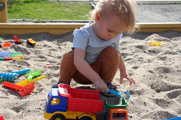 Kleines Mädchen spielt im Sandkasten mit Spielzeug