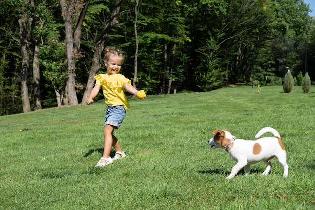 Kleines Mädchen spielt mit ihrem Hund Jack Russell Terrier im Park