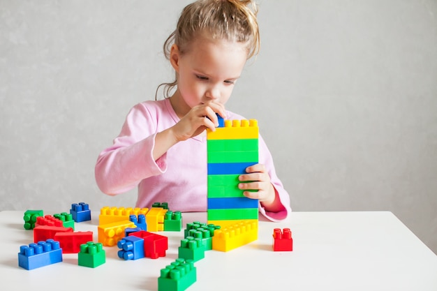 Kleines Mädchen spielt mit mehrfarbigem Plastikkonstrukteur