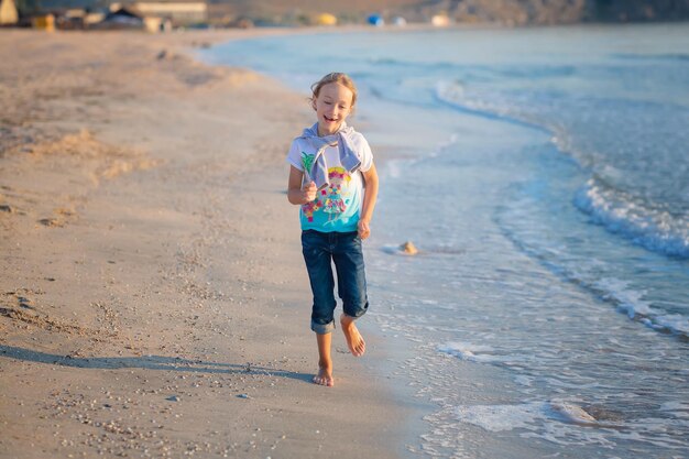 Kleines Mädchen spielt mit Sand am Strand Ein fröhliches Kind Das Konzept der Sommerferien