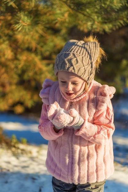 Kleines Mädchen spielt mit Schnee im Winterwald. Glückliche Kindheit. Winterspaß-Urlaubskonzept