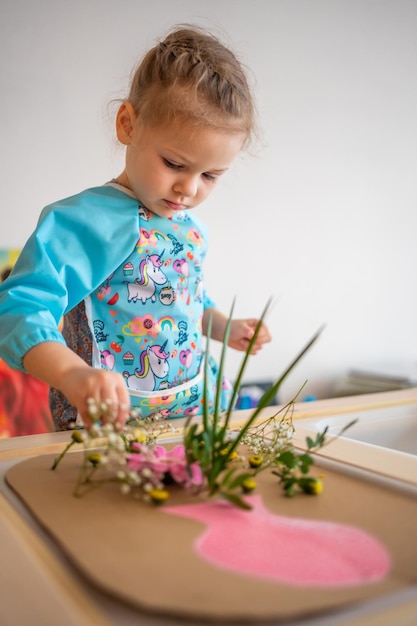 Kleines Mädchen spielt mit sensorischem Spiel und macht Herbarium zur sensorischen Entwicklung und erlebt themenbezogene Wechselstrom