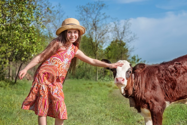 Kleines Mädchen streichelt ein Kalb auf einem Feld.