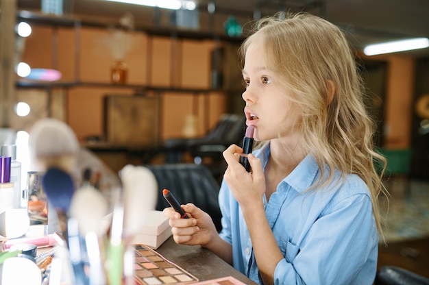 Kleines Mädchen trägt Pomade am Spiegel im Make-up-Salon auf