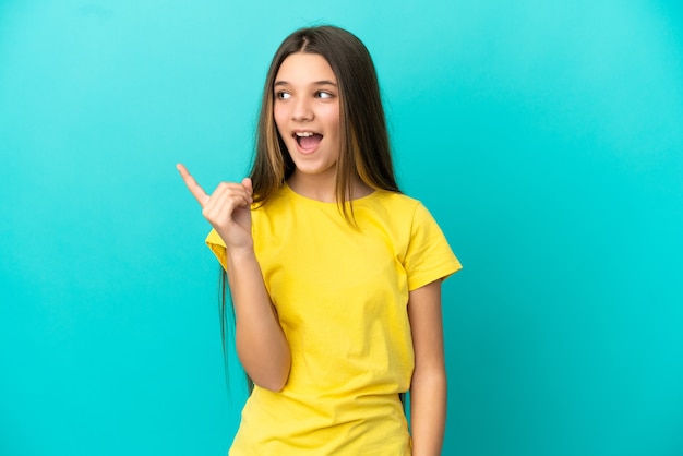 Kleines Mädchen über isoliertem blauem Hintergrund, das beabsichtigt, die Lösung zu realisieren, während es einen Finger hochhebt