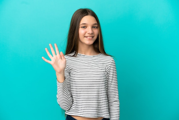 Kleines Mädchen über isoliertem blauem Hintergrund, das mit der Hand mit glücklichem Ausdruck grüßt