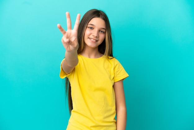 Kleines Mädchen über isoliertem blauem Hintergrund glücklich und zählt drei mit den Fingern