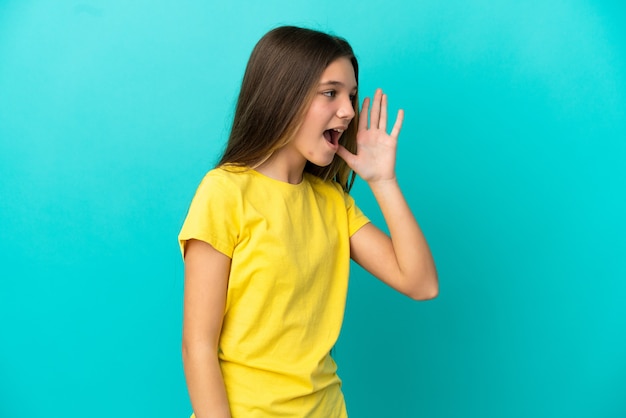 Kleines Mädchen über isolierter blauer Oberfläche schreien mit weit geöffnetem Mund zur Seite