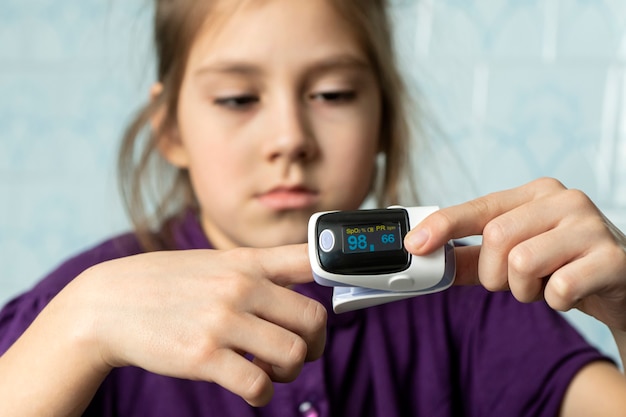 Kleines Mädchen, um Puls und Sauerstoffgehalt zu messen. Patient mit Pulsoximeter am Finger zur Überwachung