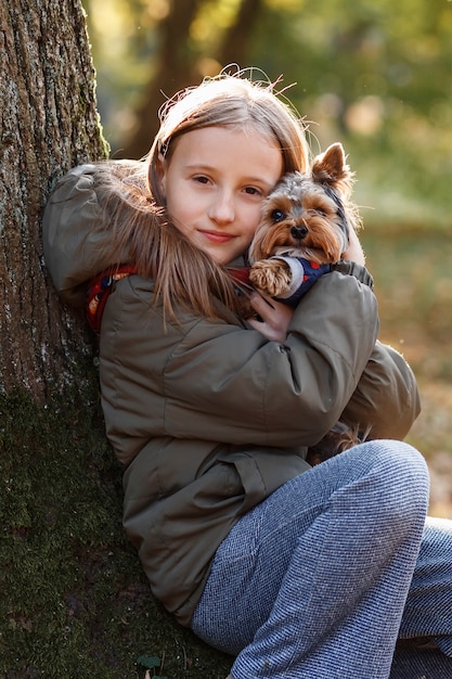 Kleines Mädchen umarmt einen Hund auf einem Hintergrund des Herbstparks