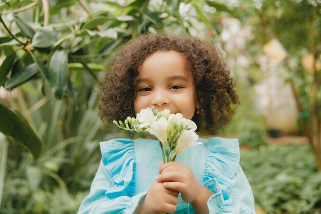 Kleines Mädchen, umgeben von tropischen Blättern Porträt eines dunkelhäutigen Kindes mit dunklem Haar Naturkosmetik Gesundheit Sauberkeit