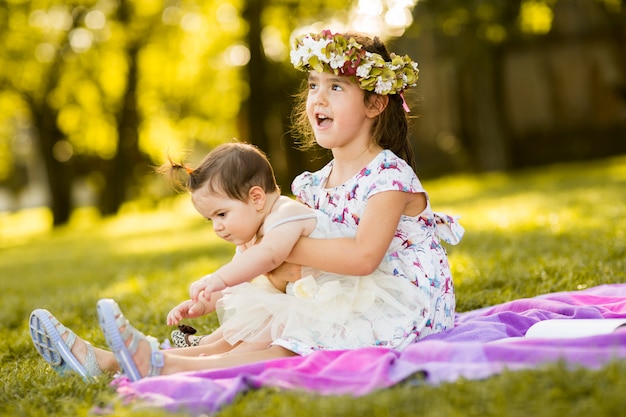 Kleines Mädchen und Baby, die im Gras sitzen