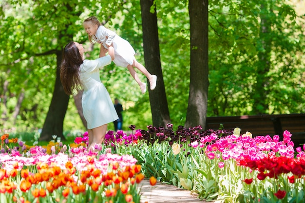 Kleines Mädchen und glückliche Mutter, die warmen Tag im bloomig Tulpengarten genießt