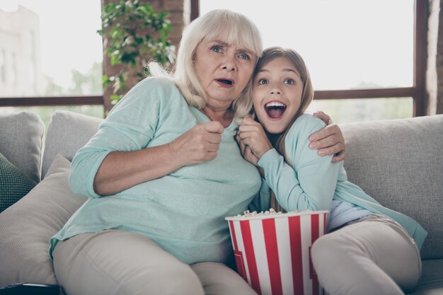 Kleines Mädchen und Großmutter sitzen auf der Couch