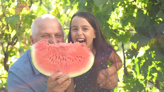 kleines Mädchen und Großvater mit Wassermelone lächeln und essen