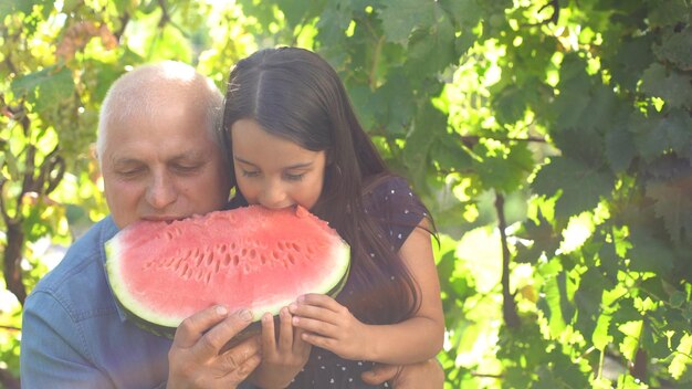 kleines Mädchen und Großvater mit Wassermelone lächeln und essen