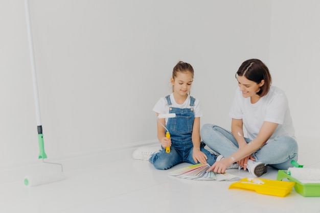 Kleines Mädchen und ihre Mutter sitzen auf dem Boden