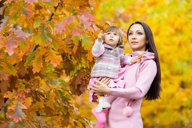 Kleines Mädchen und ihre Mutter spielen im Herbstpark.