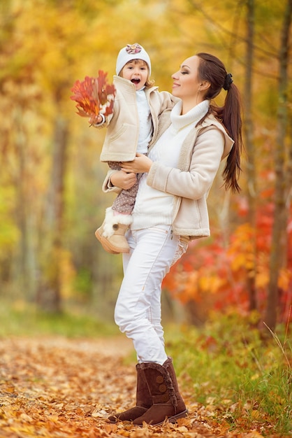 Kleines Mädchen und ihre Mutter spielen im Herbstpark.