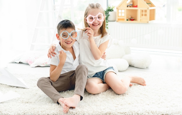 Kleines Mädchen und Junge, die Papierbrille tragen