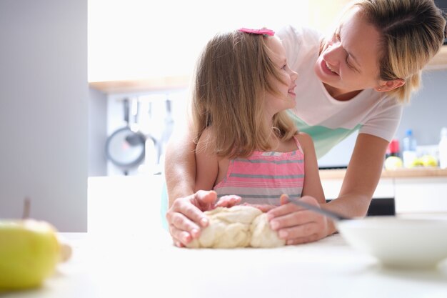 Kleines Mädchen und Mutter, die zu Hause Teigkuchen machen. Kinderbetreuungskonzept