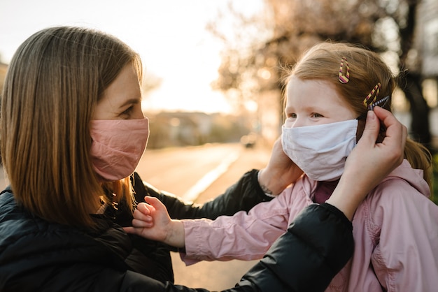 Kleines Mädchen und Mutter tragen Masken auf der Straße