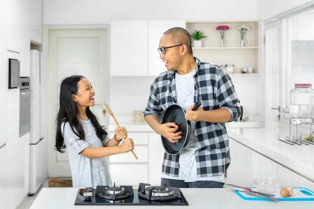 Kleines Mädchen und Vater singen gemeinsam in der Küche