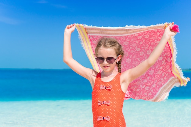 Kleines Mädchen viel Spaß mit Strand Pareo im tropischen Urlaub