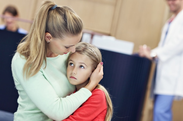 kleines Mädchen weint, während es mit ihrer Mutter bei einem Arzt nach Rücksprache ist