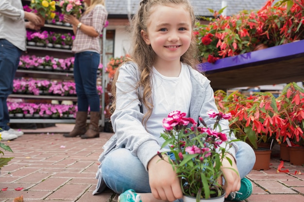 Kleines Mädchen, welches die Blumen sitzen auf Pfad hält