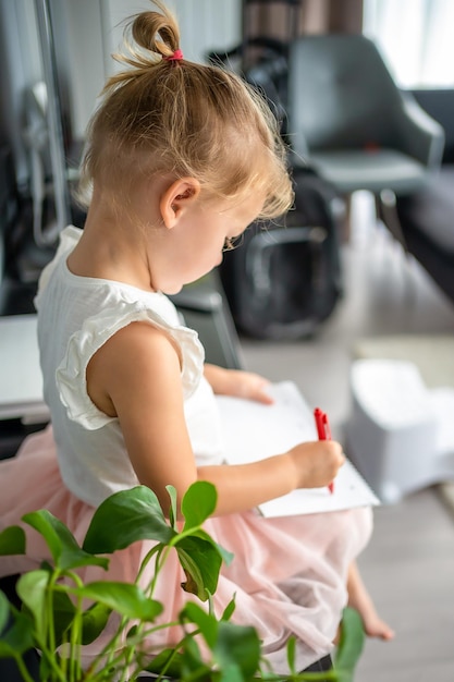 Kleines Mädchen zeichnet oder schreibt zu Hause mit rotem Stift Kreativität und Bildungskonzept für Kinder