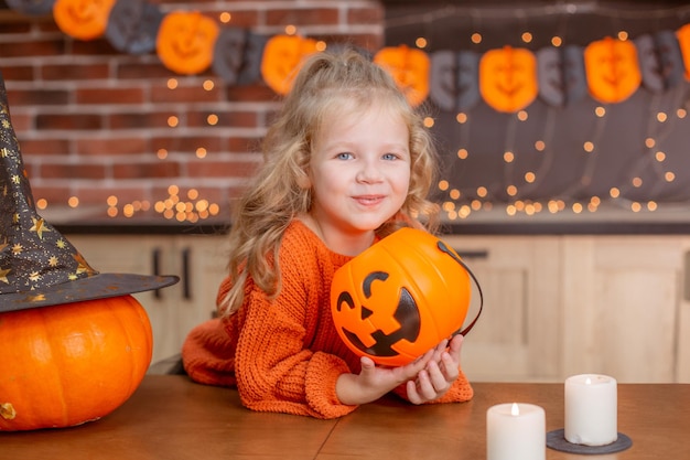 Kleines Mädchen zu Hause in der Küche am Tisch mit einem Kürbis für Halloween