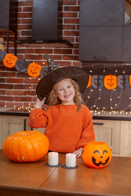 Kleines Mädchen zu Hause in der Küche am Tisch mit einem Kürbis für Halloween