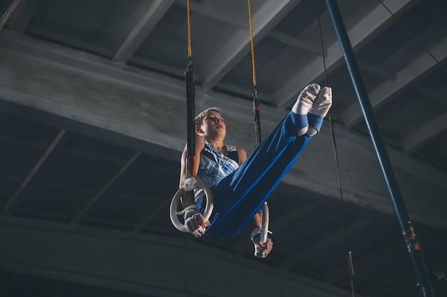 Kleines männliches Turnertraining im Fitnessstudio flexibel und aktiv Kaukasischer, fitter kleiner Junge in Sportbekleidung, der in Übungen für das Kraftgleichgewicht übt