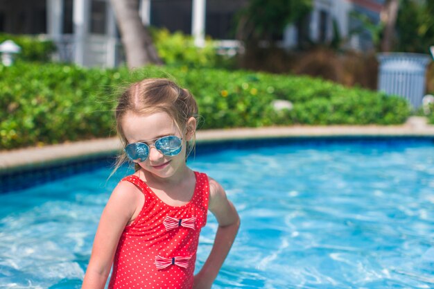 Kleines nettes glückliches Mädchen schwimmt im Swimmingpool