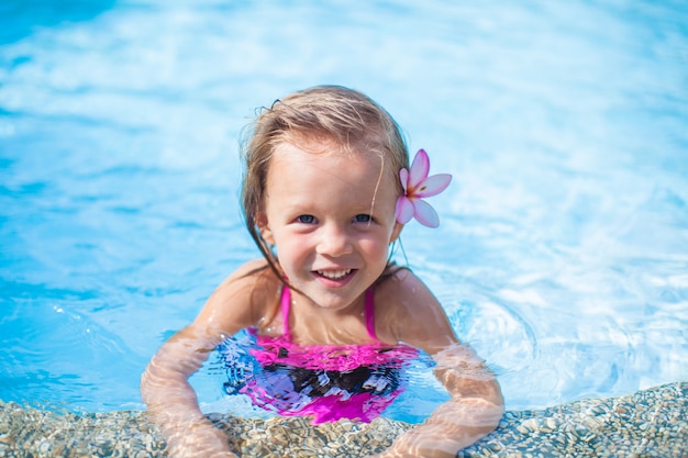 Kleines nettes Mädchen mit Blume hinter ihrem Ohr im Swimmingpool