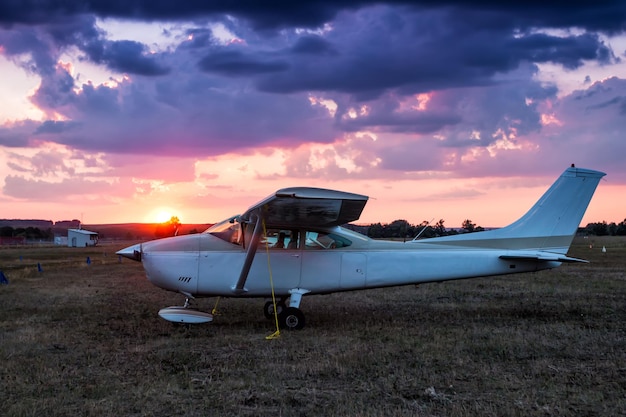 Kleines Privatflugzeug, das bei malerischem Sonnenuntergang am Flugplatz geparkt ist