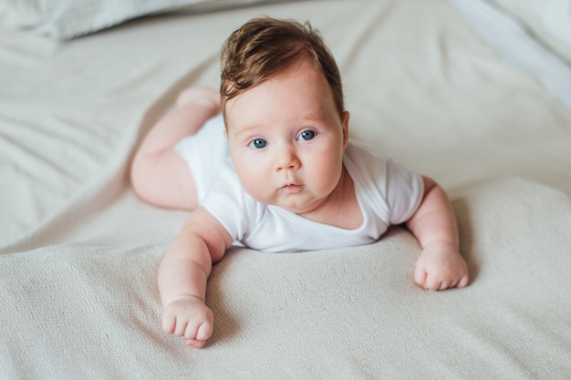 Kleines Säuglingsbaby, das Bauchzeit auf Bett zu Hause hat.