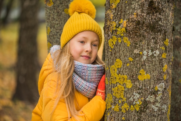 Kleines schönes blondes Mädchen in gelber Kleidung, Herbst