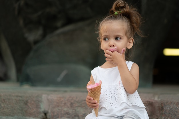 Kleines schönes Mädchen, das ein Eis isst