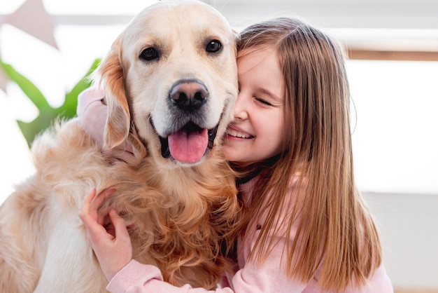 Kleines schönes Mädchen, das entzückenden goldenen Retrieverhund streichelt