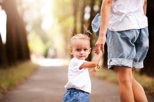 Kleines schönes Mädchen geht mit ihrer Mutter im Park spazieren
