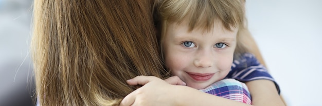 Kleines schönes Mädchen umarmt ihre Mutter und lächelndes Porträt. Soziale Garantien für Frauen mit Kindern während des Scheidungskonzepts