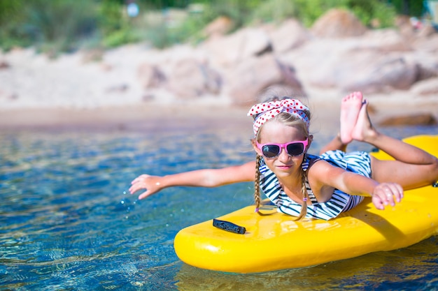 Kleines schönes nettes Mädchen, das im klaren blauen Meer Kayak fährt