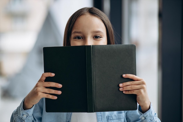 Kleines Schulmädchen mit Buch zu Hause