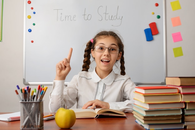 Kleines Schulmädchen zeigt mit dem Zeigefinger nach oben