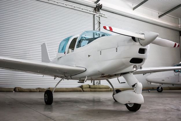 Kleines Sportflugzeug mit geöffnetem Cockpitverdeck im Hangar