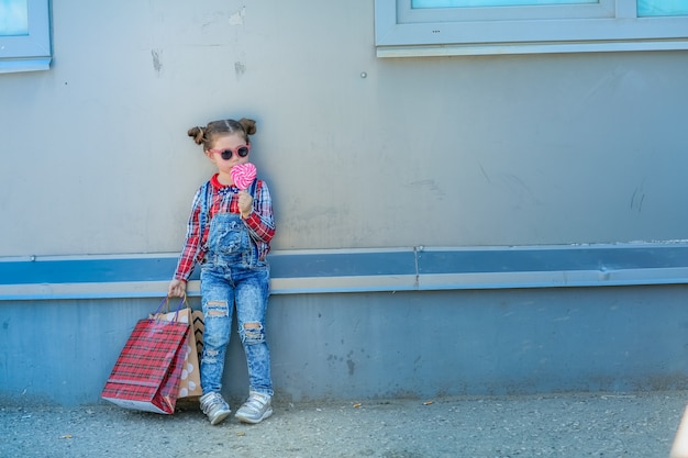 Kleines stilvolles Mädchen in Sonnenbrille und zwei Zöpfen auf ihrem Kopf