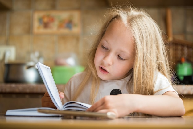 Kleines Studentenmädchen, das zu Hause Buch liest